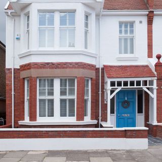 house exterior with bricked and white wall and blue door