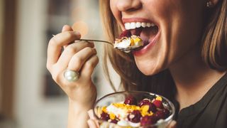 Woman eating bowl of yoghurt and fruit