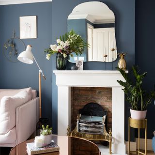 A navy-painted living room with a white fireplace and golden accessories