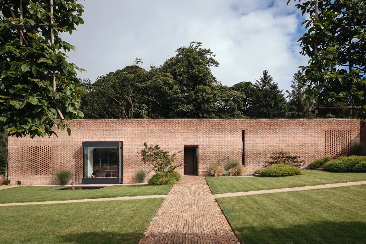 A long red brick home with a brick paved path leading to the front door