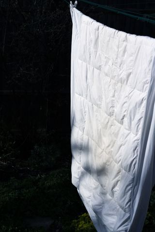 A white duvet airing outside on a clothes line