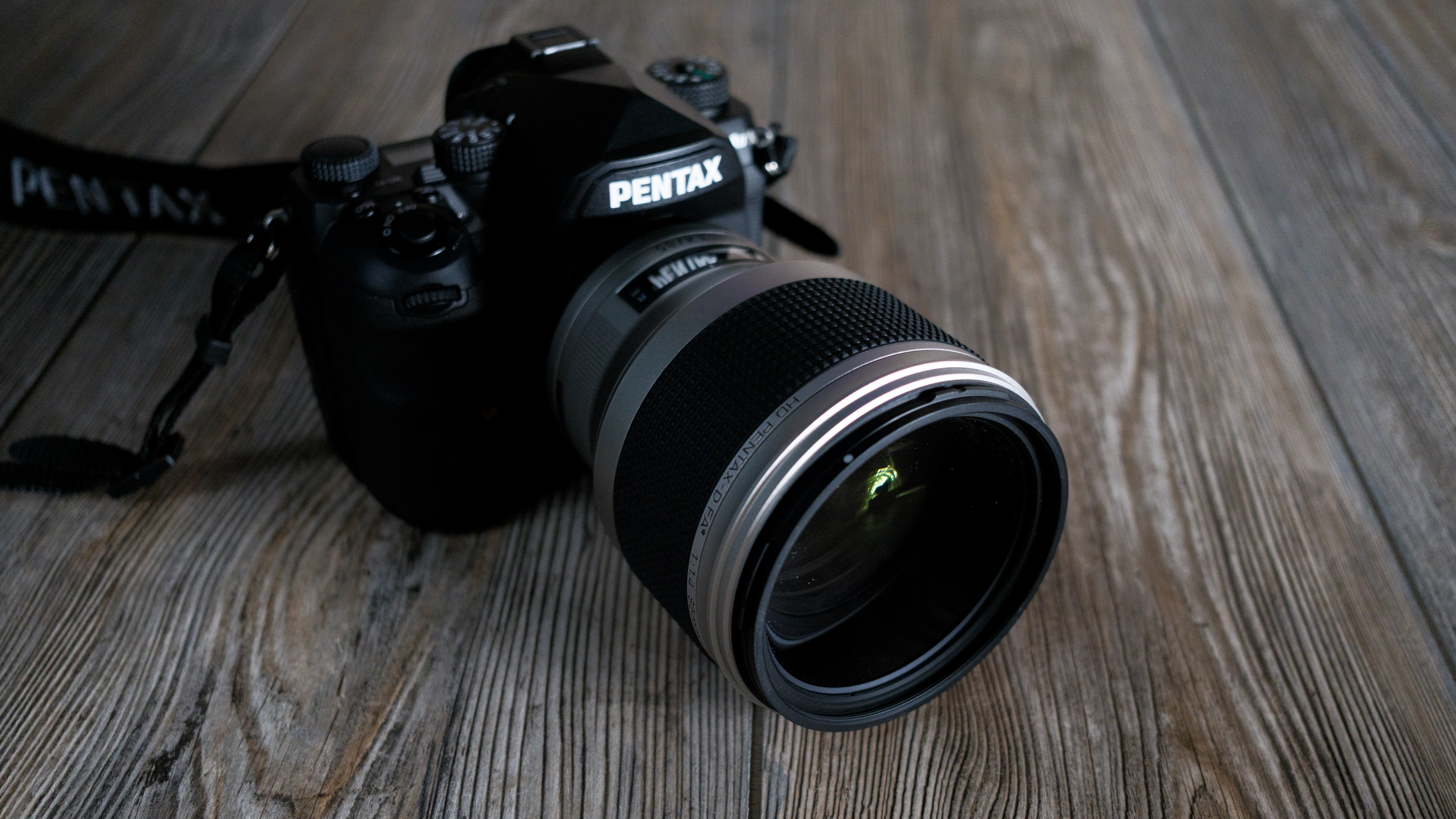 The Pentax 85mm f/1.4 SDM AW on a wood background