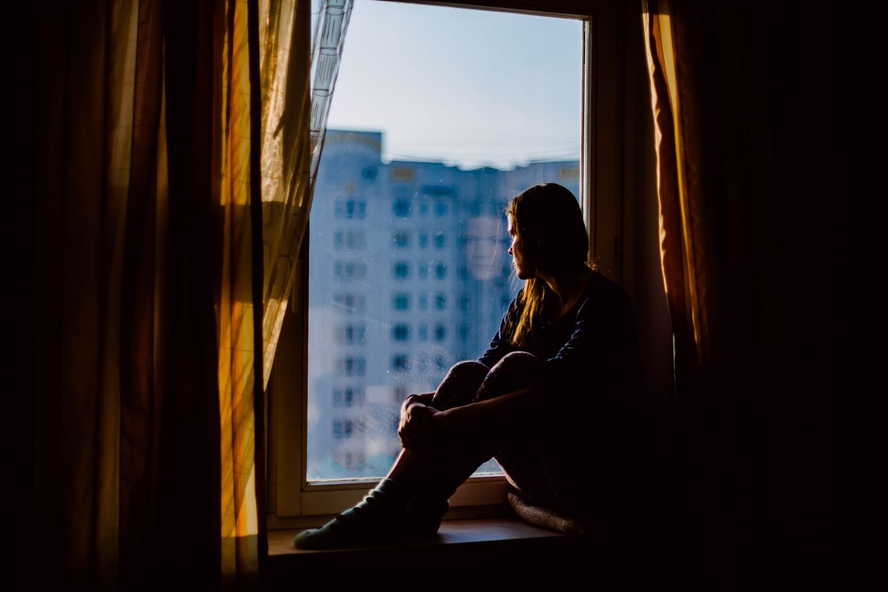 A woman coping with the symptoms of depression stares out of the window