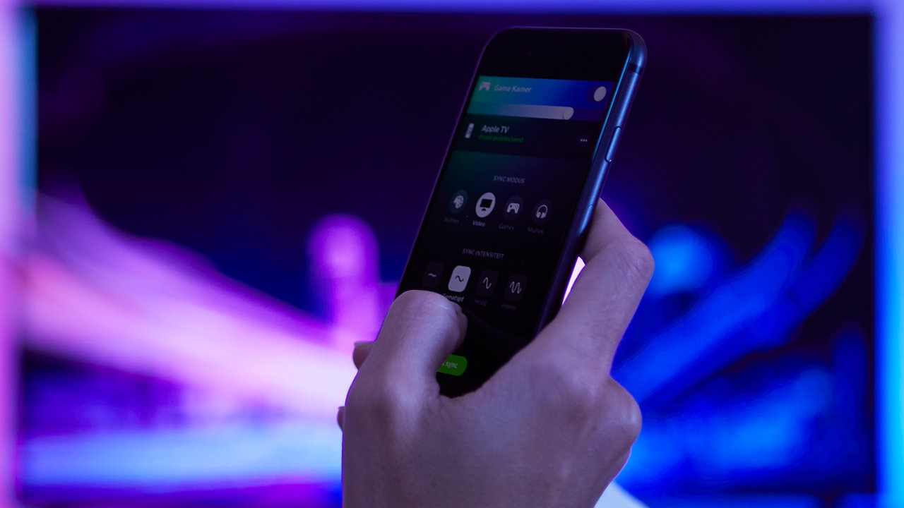 Person's hand holding phone using Philips Hue app