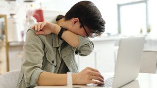 A man sneezing while at his laptop