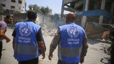 Members of the UNRWA walk among the rubble of a damaged school in Gaza