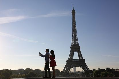 Tourists snap a selfie near the Eiffel Tower.
