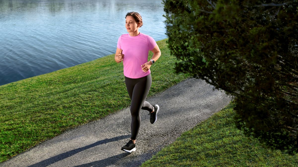 Woman running by a canal wearing a Garmin Forerunner 55 watch