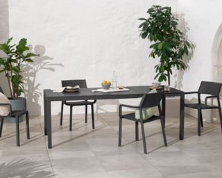 Nardi 6-8 Seat Extending Dining Table in garden with chairs around, bottle of water and plates on the table