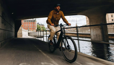 Man cycling under a canal bridge 