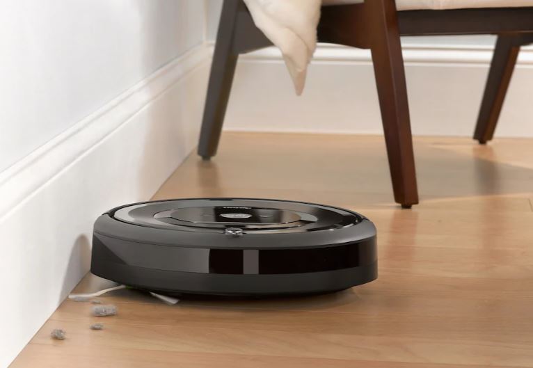 iRobot Roomba e5 membersihkan lantai keras dengan kursi di latar belakang