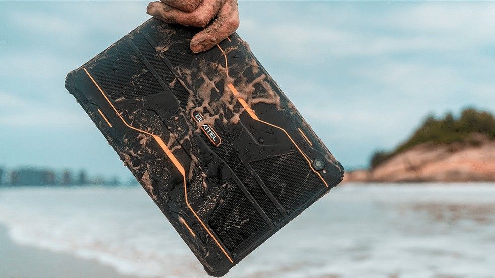 Oukitel RT1, one of the best rugged tablets, covered in sand and being carried on the beach