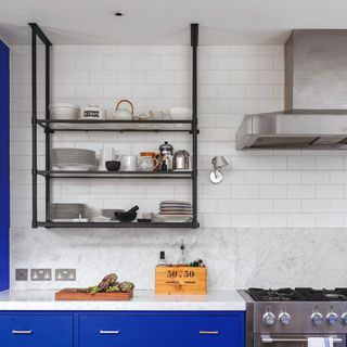 Open kitchen shelving display with dinnerware in white kitchen with blue cabinets