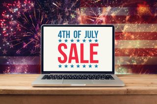 The words &quot;4th of July SALE&quot; on a laptop screen, against a background of the US flag with fireworks