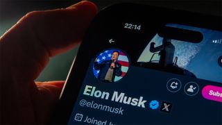 Person holds phone displaying X account of Elon Musk