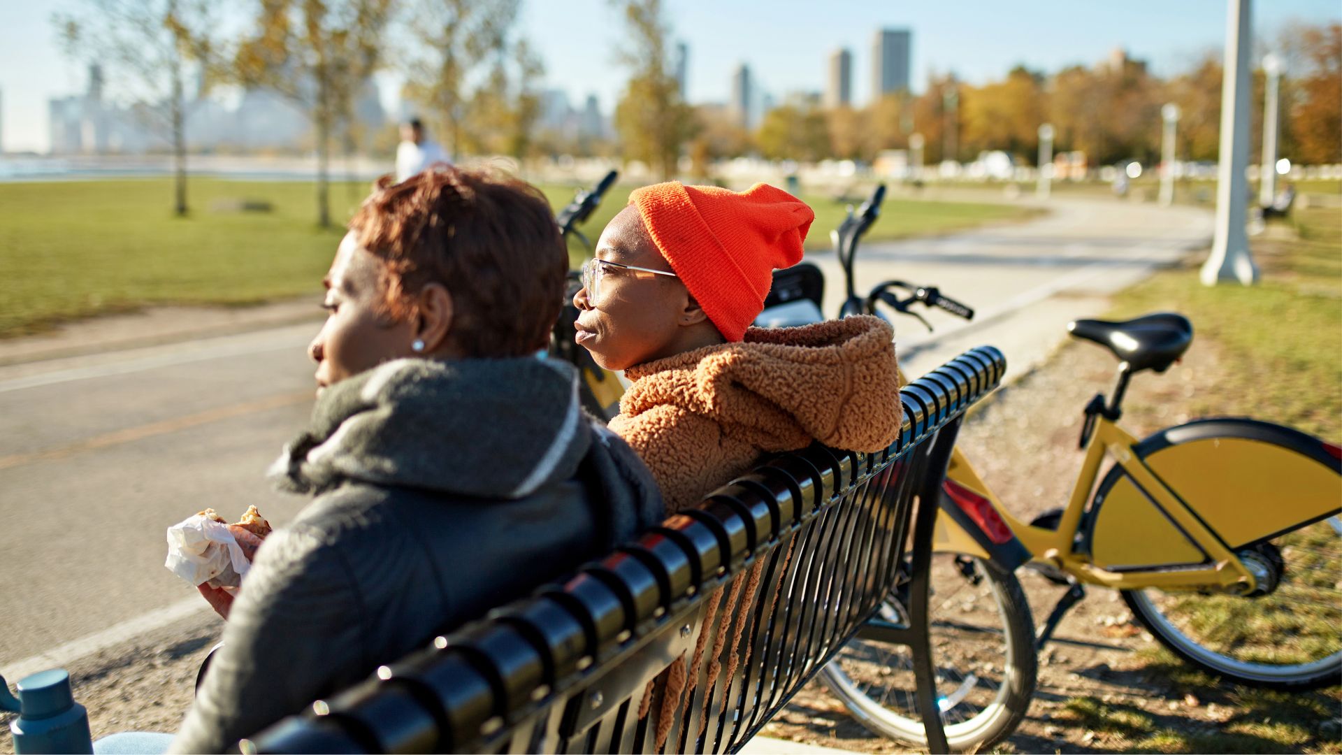 Women sitting down on bench and eating next to bike