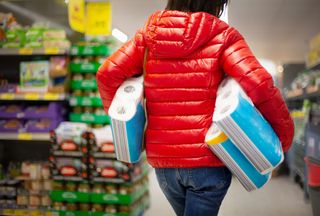woman in red coat bulk buying toilet rolls in the supermarket