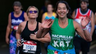 A runner in the London Marathon 2021 wearing a green running vest with the logo of Macmillan Cancer Support on it