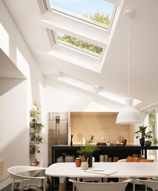 stylish rooflights in extension with angled ceiling and contemporary white scheme, an example of effective kitchen planning by velux