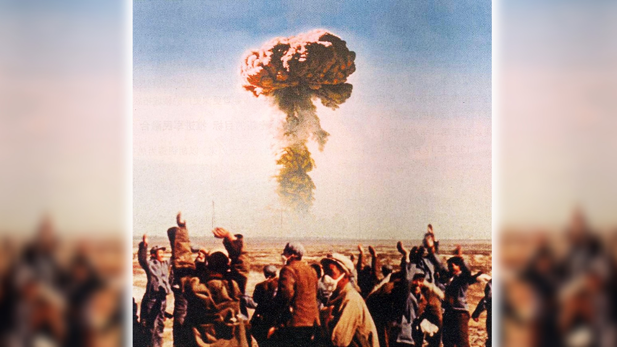 a nuclear mushroom cloud appears in the sky over the horizon with a crowd of Chinese workers in the foreground