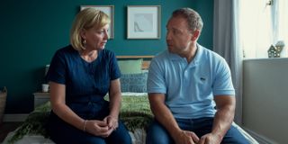 Christine Tremarco as manda miller and stephan graham as eddie miller sitting on a bed talking in the tv show adolescence
