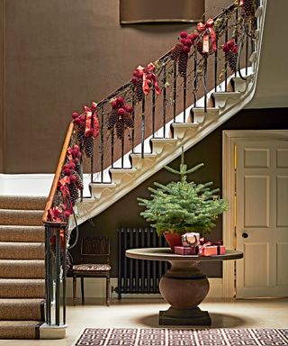 Hall with round table and Christmas tree and stair hand rail with garland