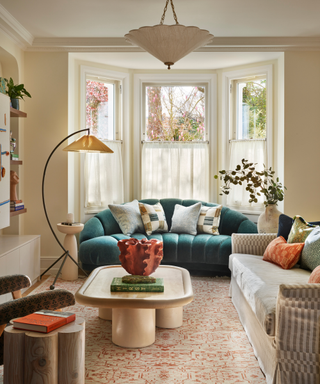 Townhouse living room with buttery colored walls, bright teal couch and sinuous coffee table with pops of orange throughout