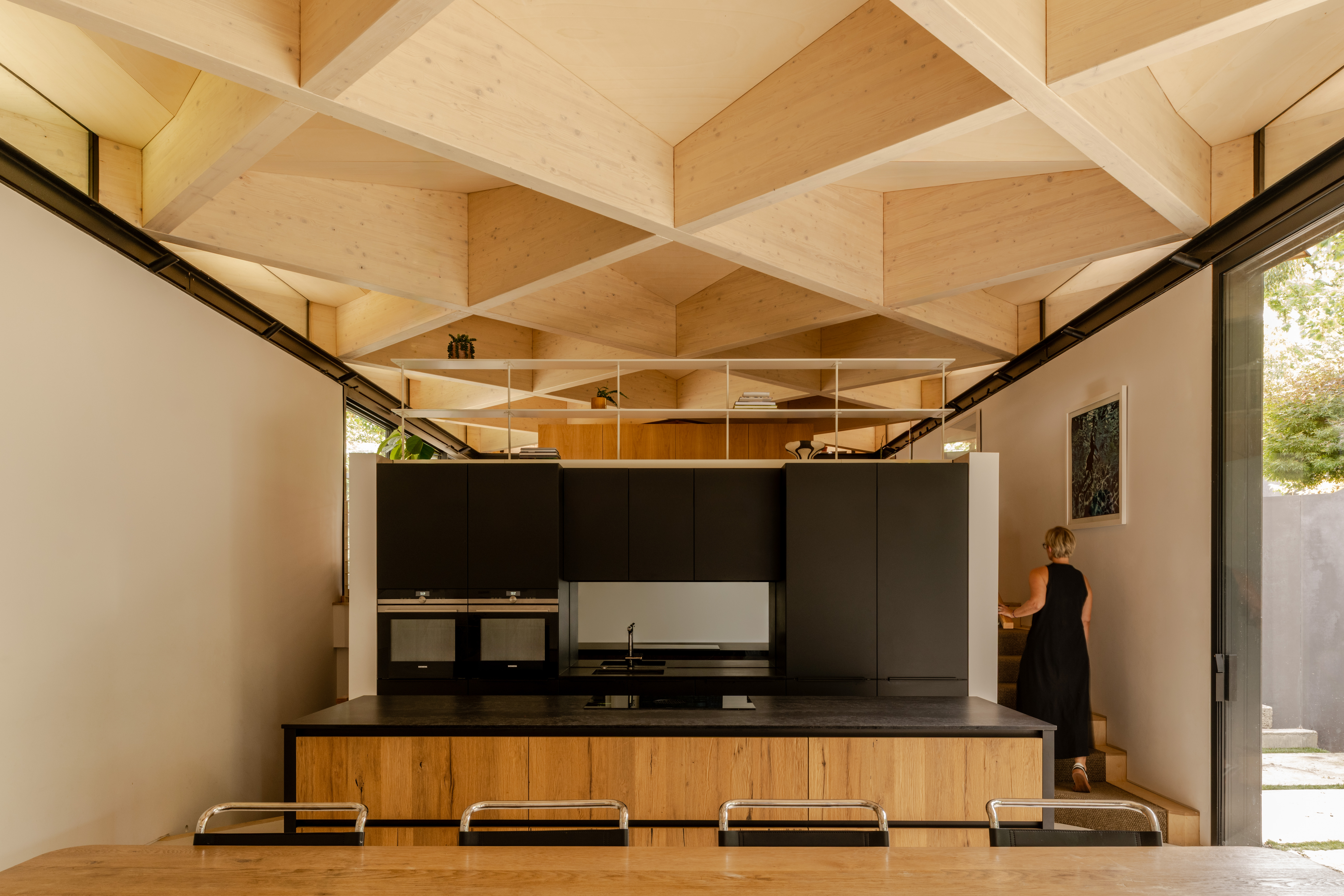 arbour house, a low, one storey home in a back year among trees, but with a distinctive angular roof