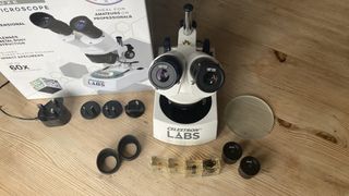 The Celestron Labs S10-60 Stereo Microscope and its accessories on a wooden table