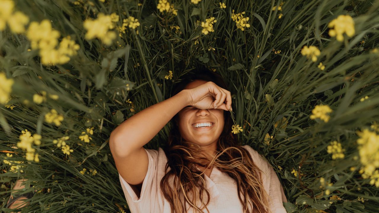 woman smiling in a field of flowers, meant to symbolize spring equinox 2022