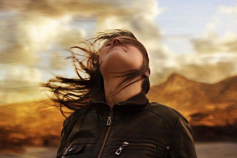 A woman tilts her head back on a windy day.