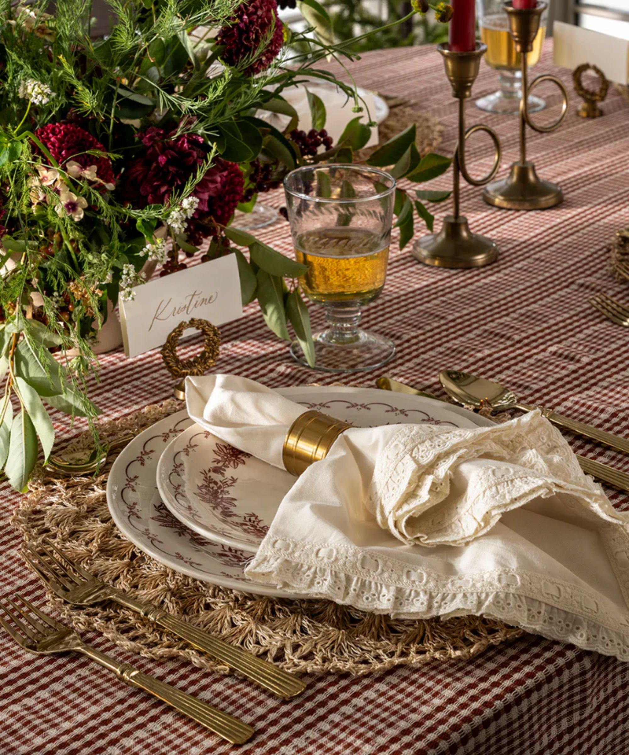 Christmas table with red gingham tablecloth, white frill napkins and gold napkin rings