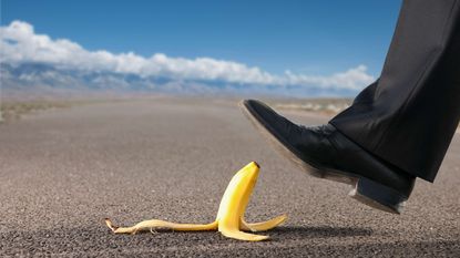 A man in a business suit steps on a banana peel.