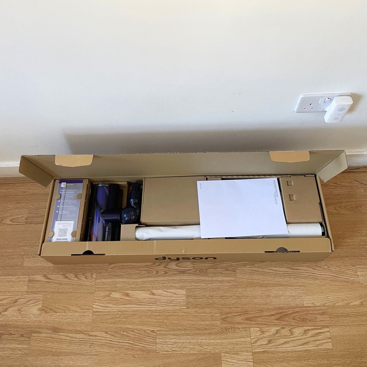 Dyson Gen5detect box with the lid open, sitting on wooden floor