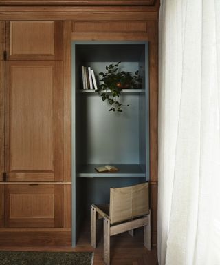 library corner with wooden wall and built in shelving painted blue.