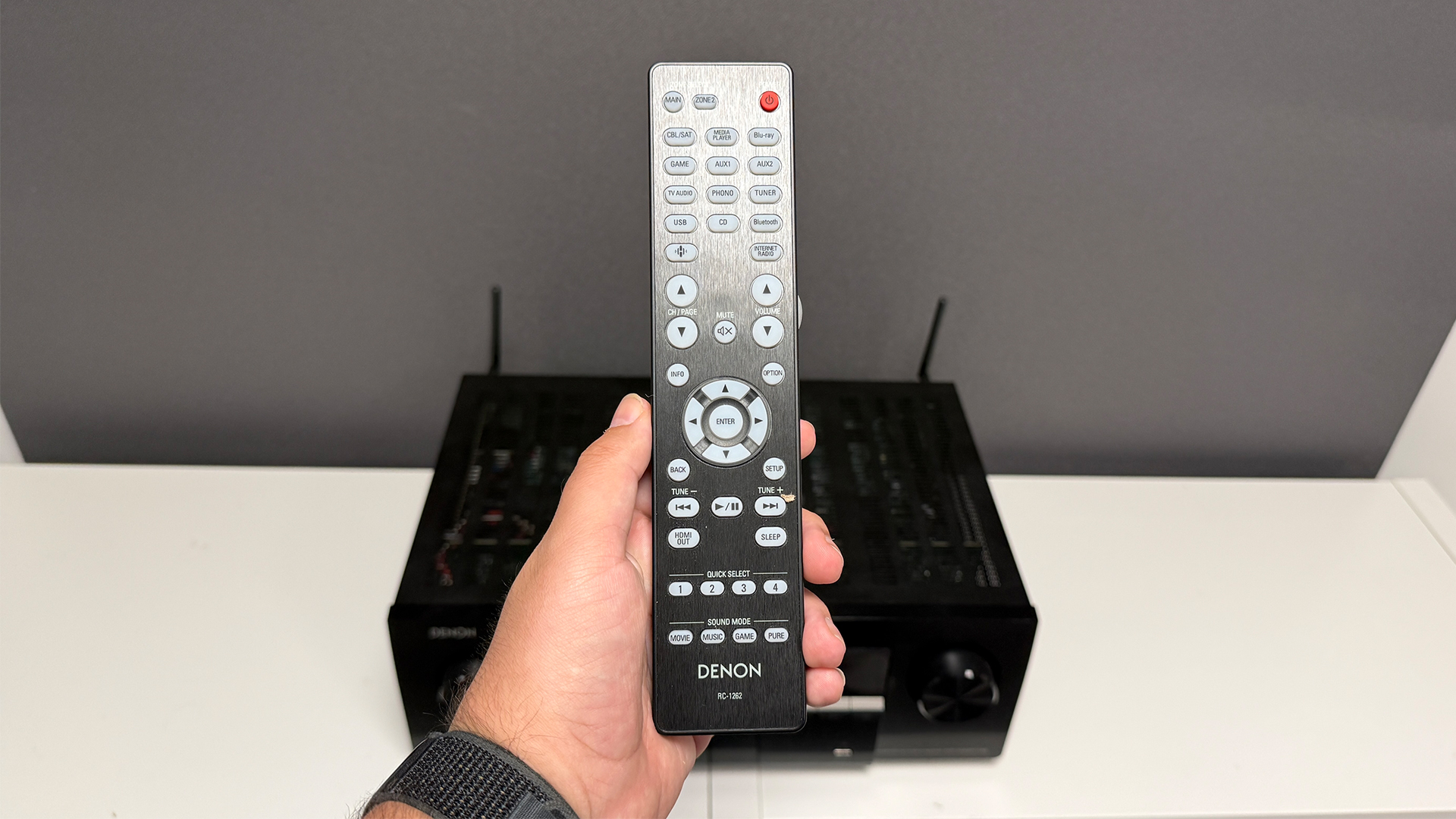 Denon AVR-X2900H home cinema amplifier with remote control held in hand above