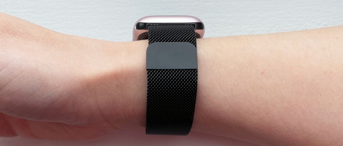 A black-coloured metal mesh watch strap wrapped around a woman&#039;s wrist.