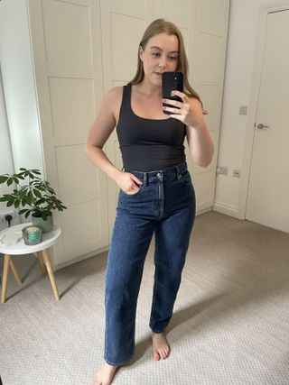 Woman wears grey tank top and blue straight leg jeans