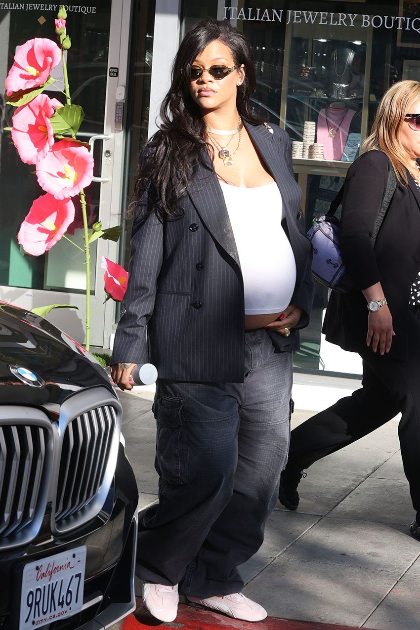 Rihanna wearing a blazer, baggy pants, and baby pink Puma Speedcat sneakers