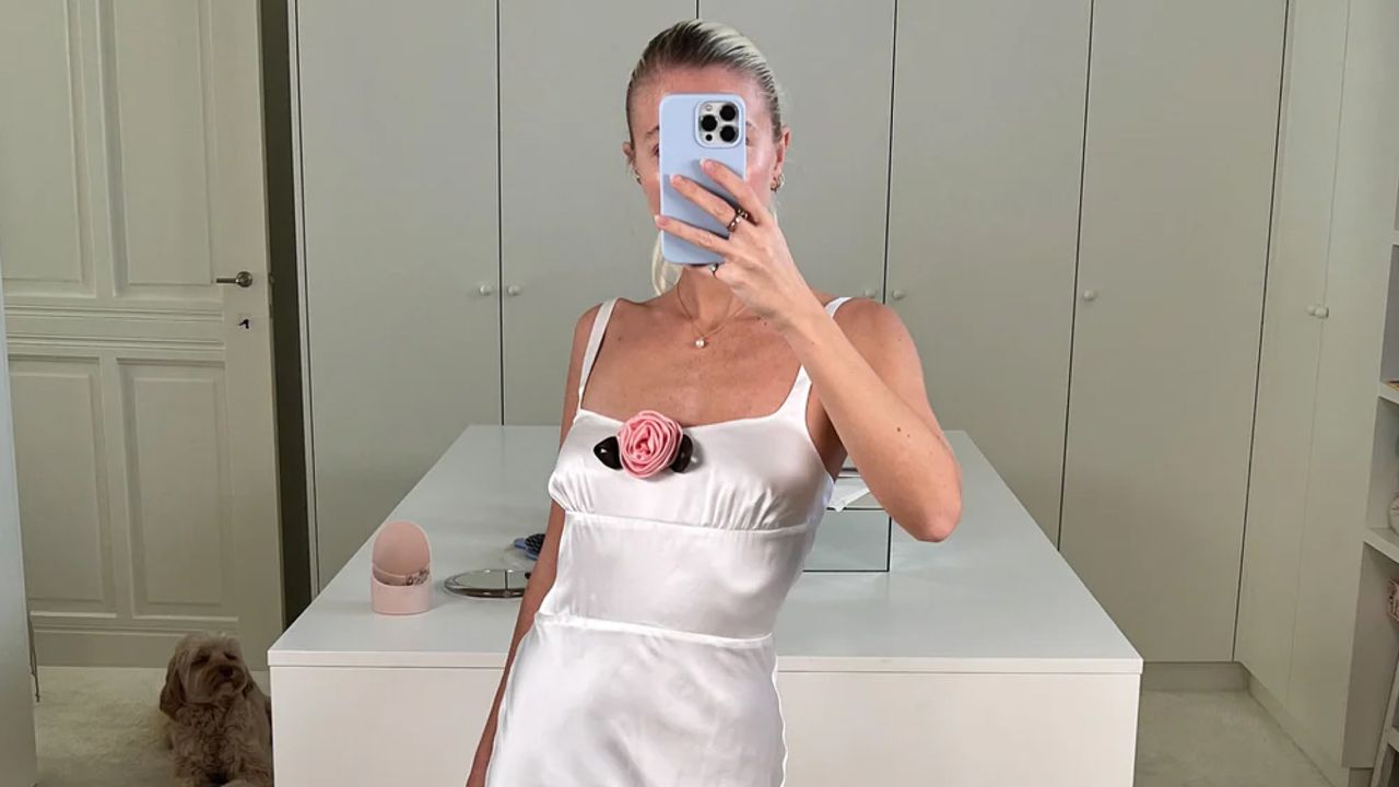 a Bernadette Antwerp bride taking a mirror selfie while wearing a white satin dress