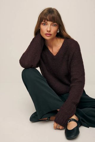 reformation winter sale woman wearing dark purple v-neck jumper and trousers