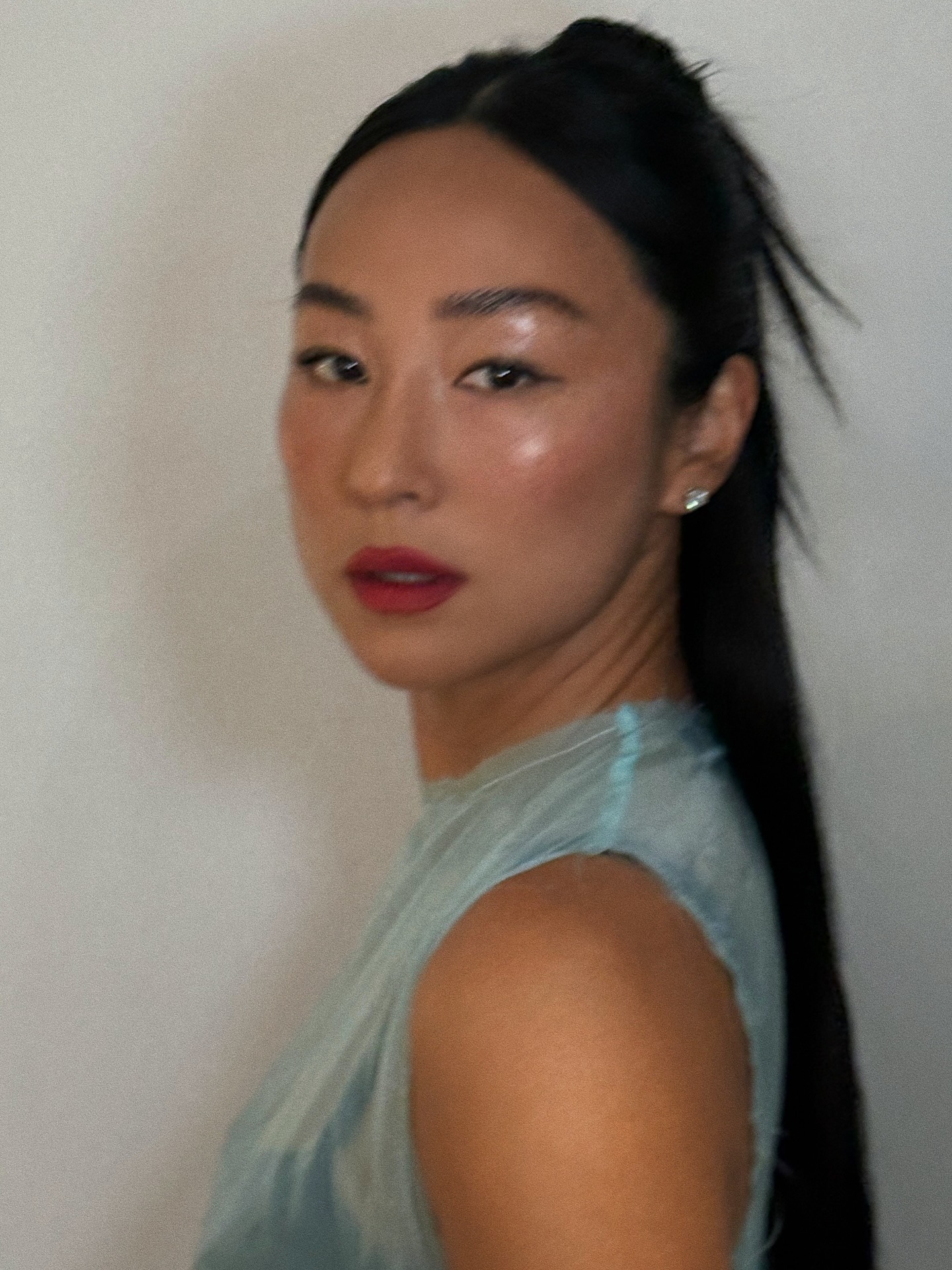 Greta Lee wearing a half-up, half-down hairstyle with a blue shiny dress