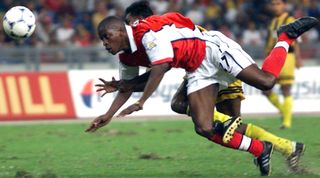 Arsenal's Kaba Diawara (front) takes a fall with a Malaysian player 19 May 1999 during a friendly match between the two teams at the National Stadium in Kuala Lumpur. Arsenal beat Malaysia 2-0. (ELECTRONIC IMAGE) AFP PHOTO/Jimin LAI (Photo by JIMIN LAI / AFP) (Photo by JIMIN LAI/AFP via Getty Images)