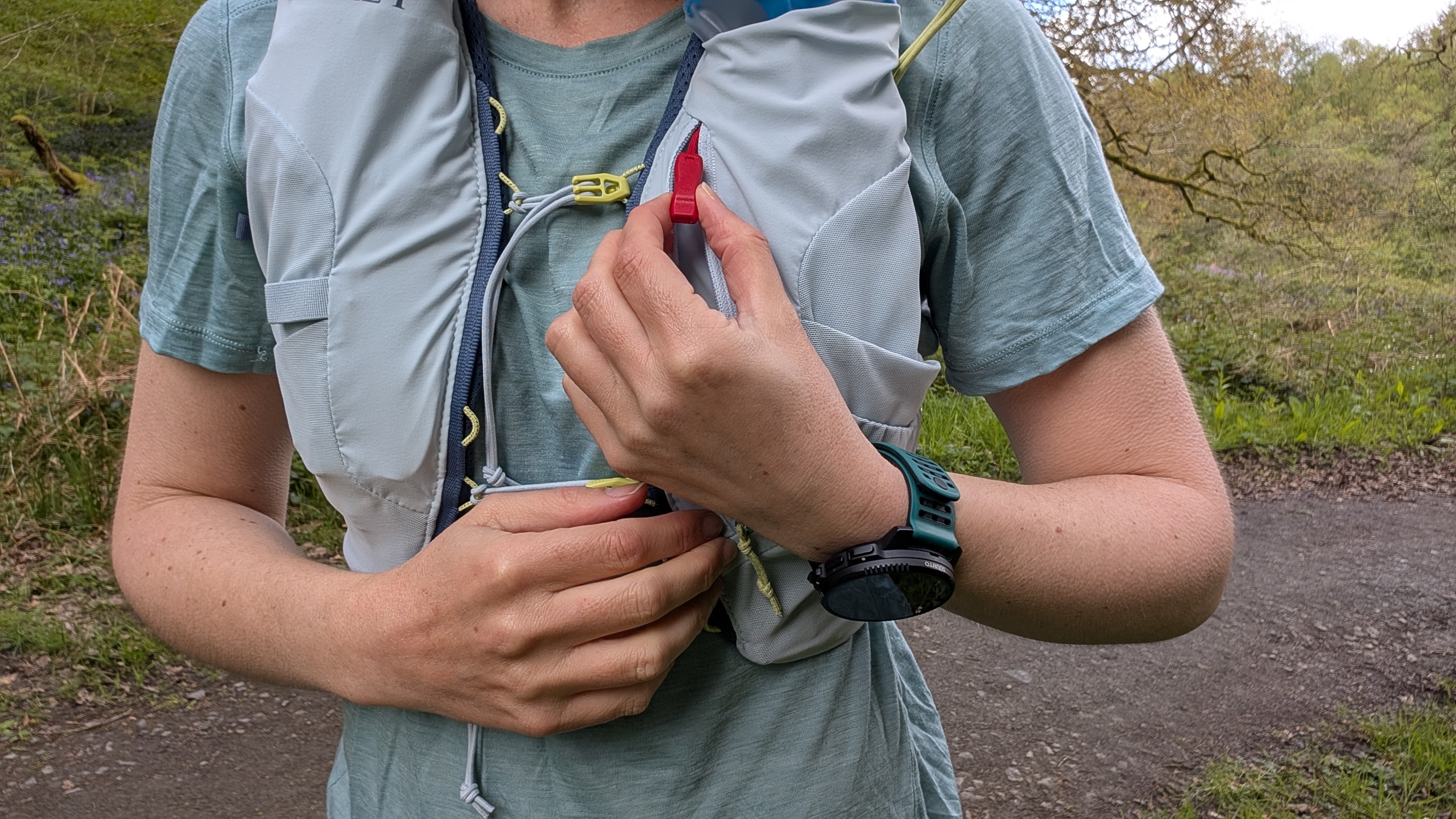 Close up of a woman trail runner showing the emergency whistle in the Osprey Dyna running vest