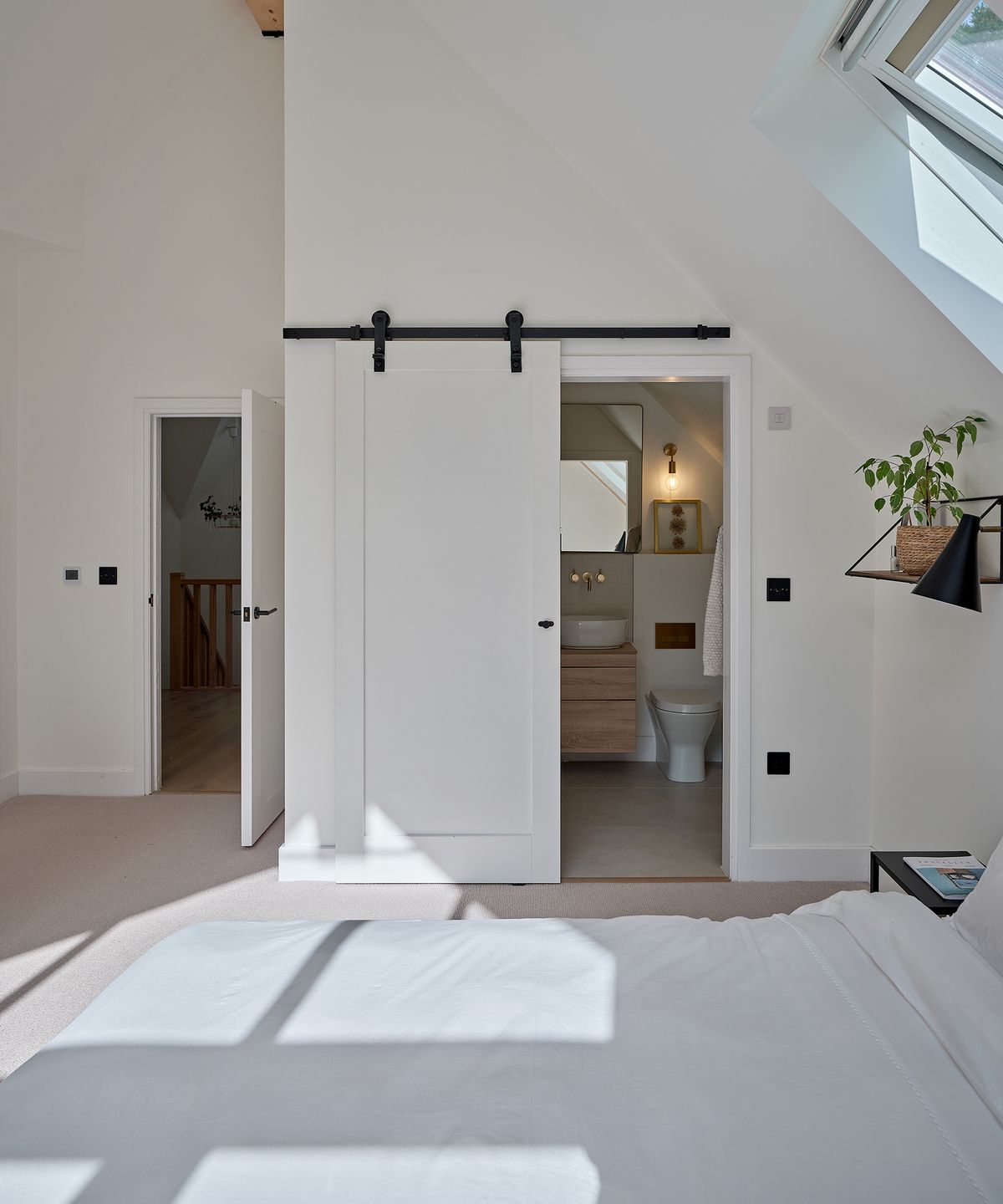 A loft bedroom of a new build home with a small ensuite bathroom with shower