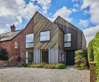 A striking exterior of a new self build constructed with SIPs and a gravel driveway out front