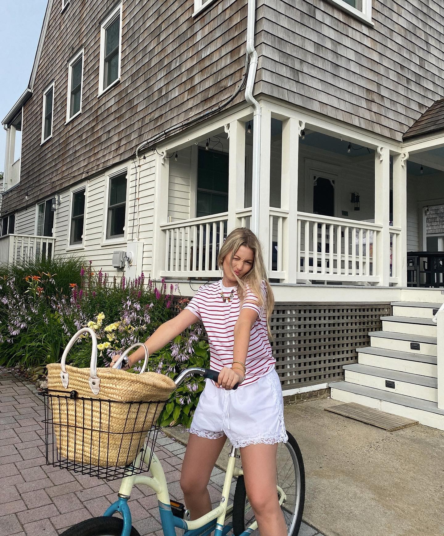 A girl wearing a striped t-shirt riding a bike with a wicker basket