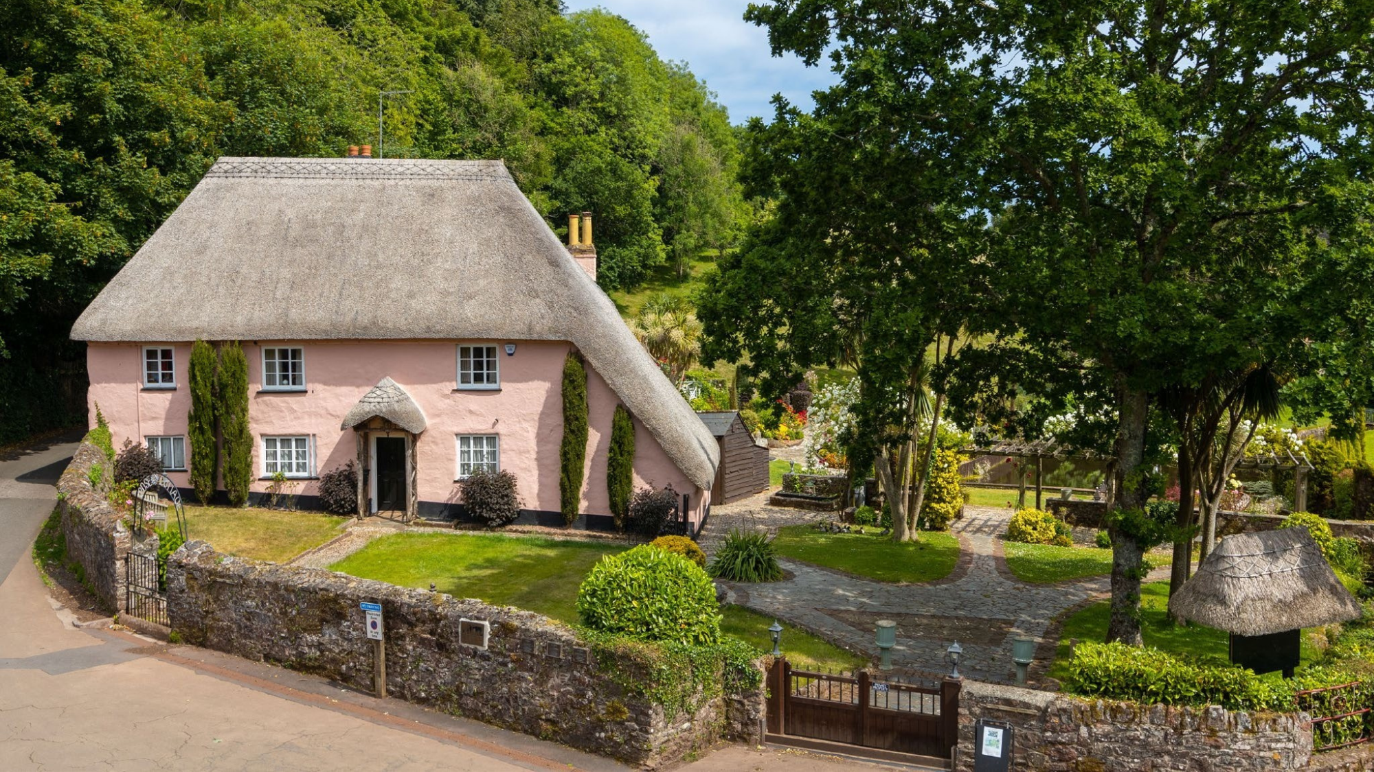 Thatched pink 18th century cottage set within manicured gardens in Devon.