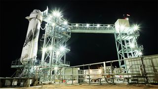 blue origin rocket on launch pad at night with complicated gantry