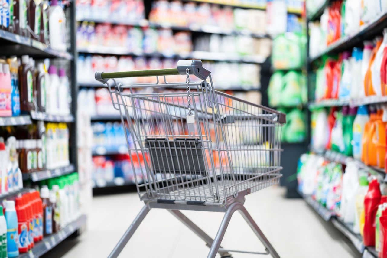 Shopping cart in cleaning aisle at store.